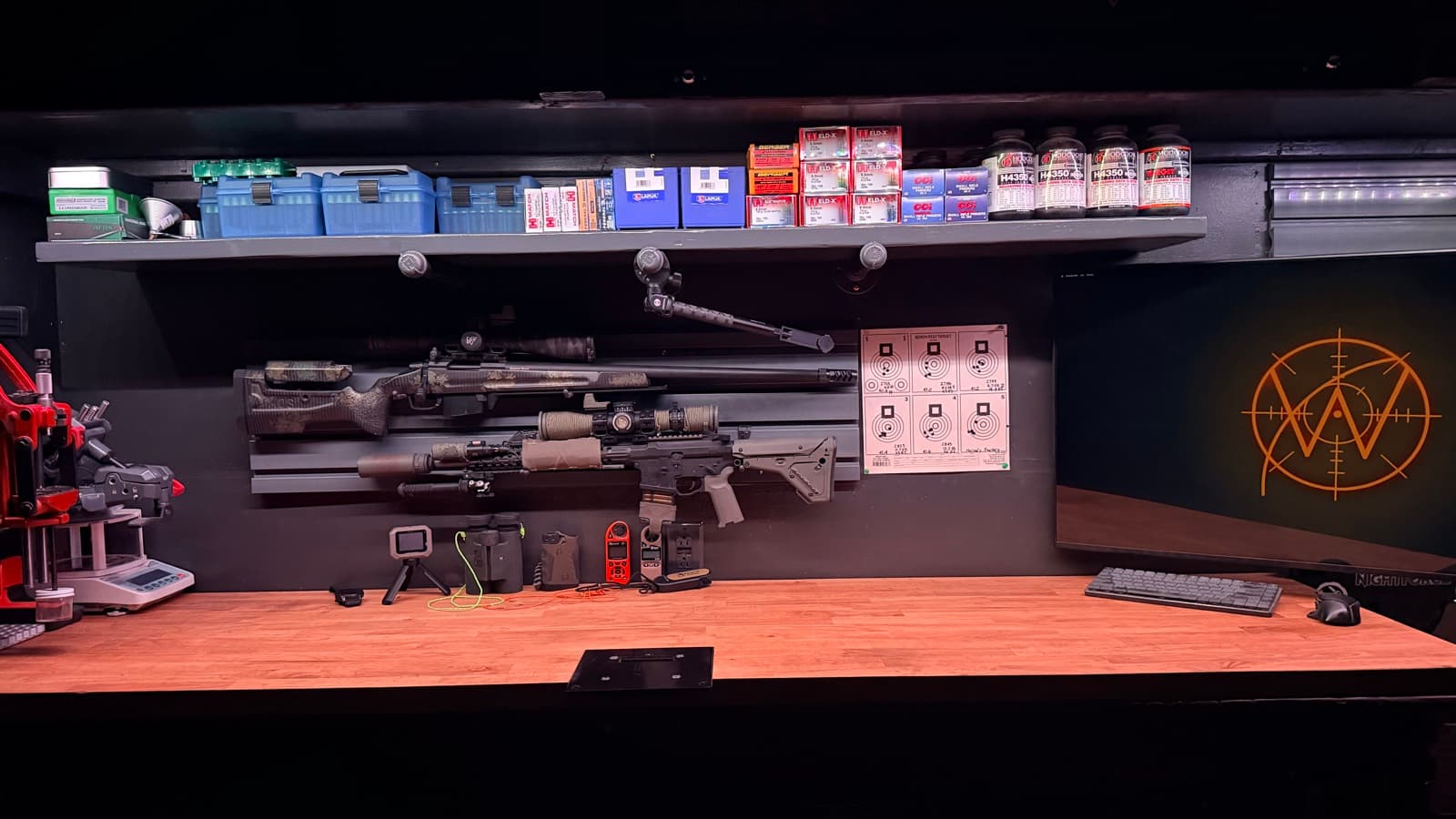 The reloading bench where Wrist Dope is built — rifles, a reloading press, a chronograph, and the Wrist Dope mark on the wall